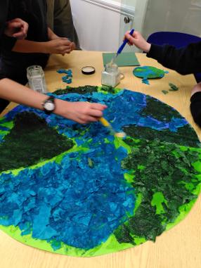 Members of the club making a découpage image of planet earth